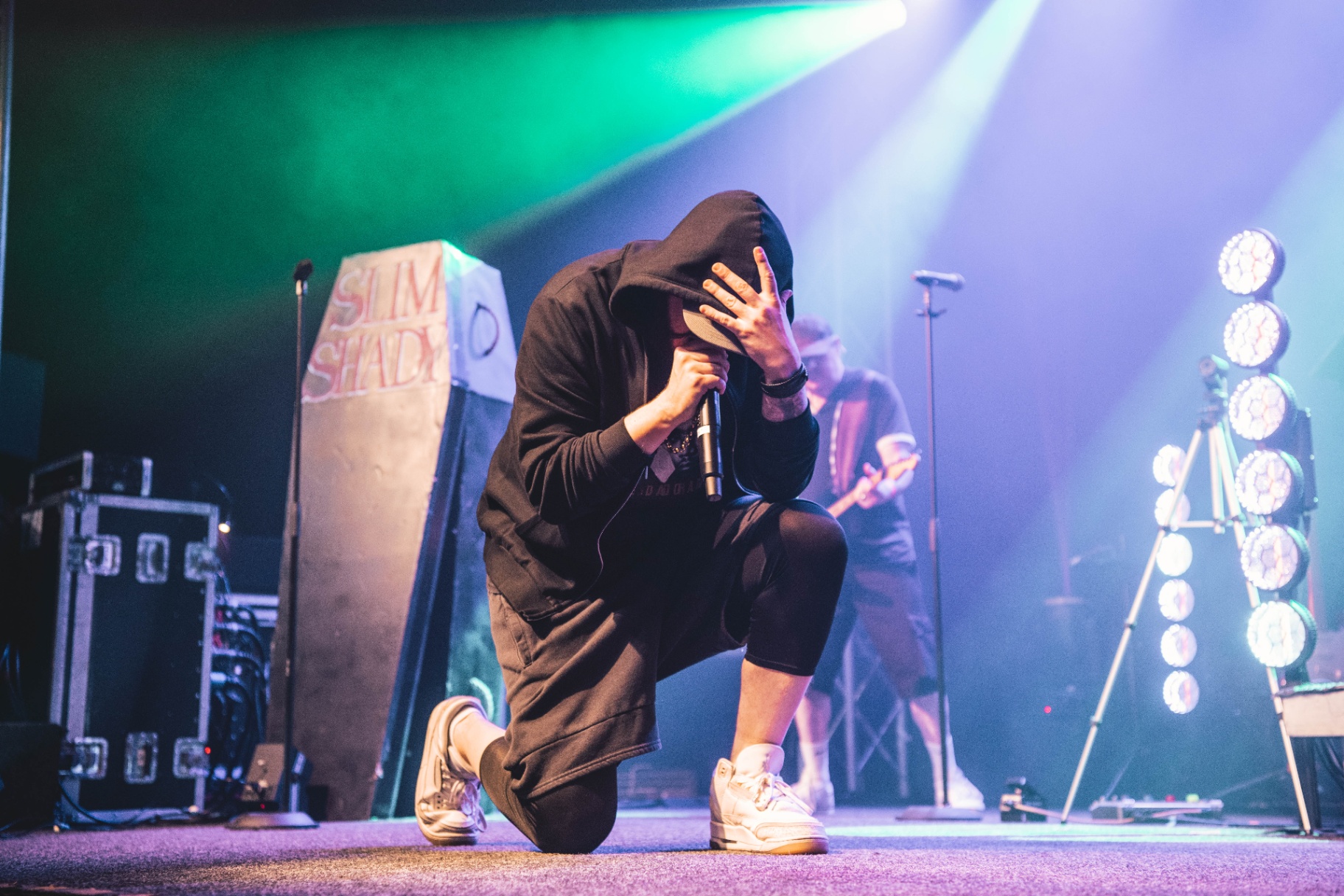Frontman James Wythes kneeling on stage in a black hoodie